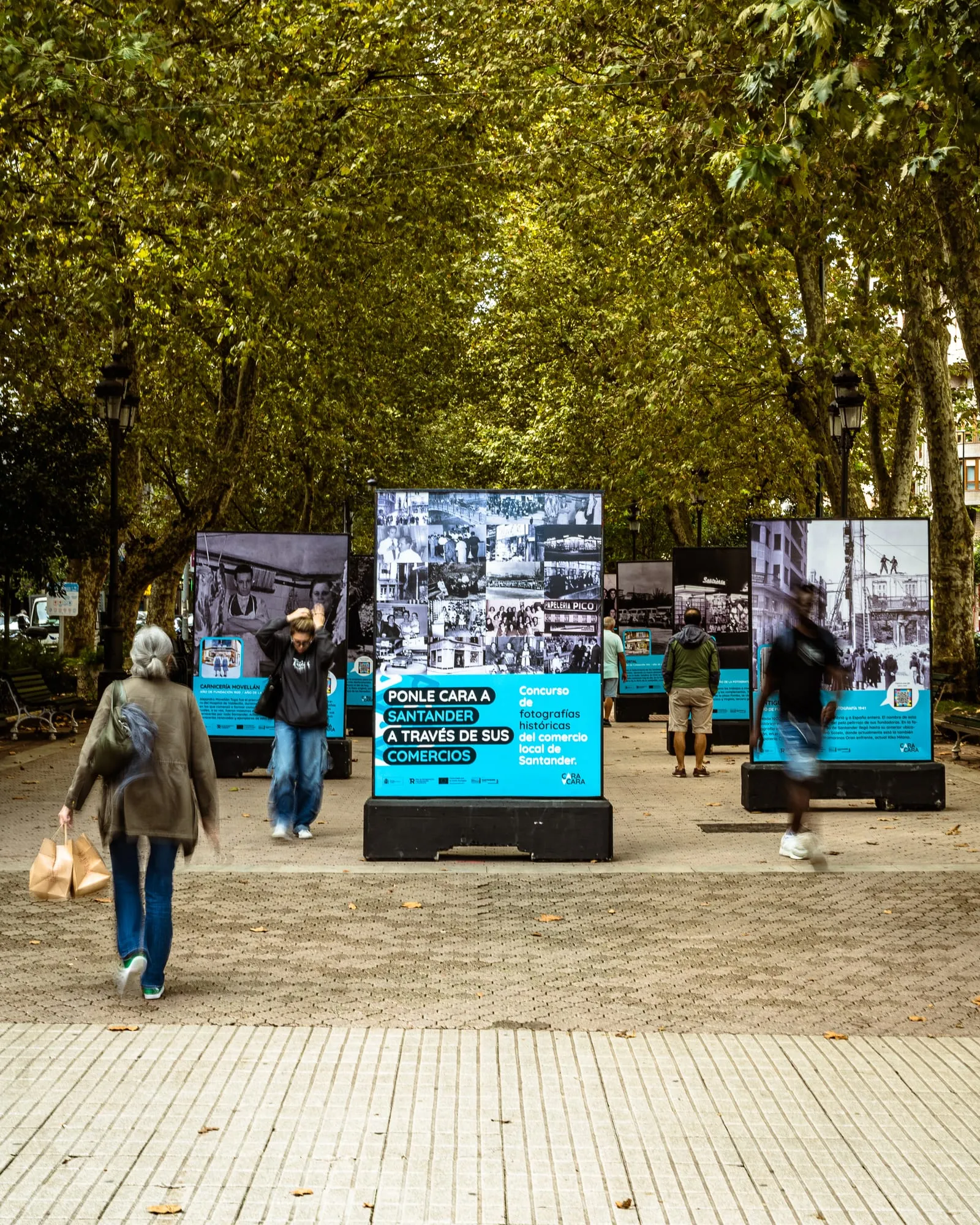 Exposición urbana de comercios históricos en la Alameda de Oviedo: paneles negros con fotos antiguas y el claim Ponle cara a Santander a través de sus comercios