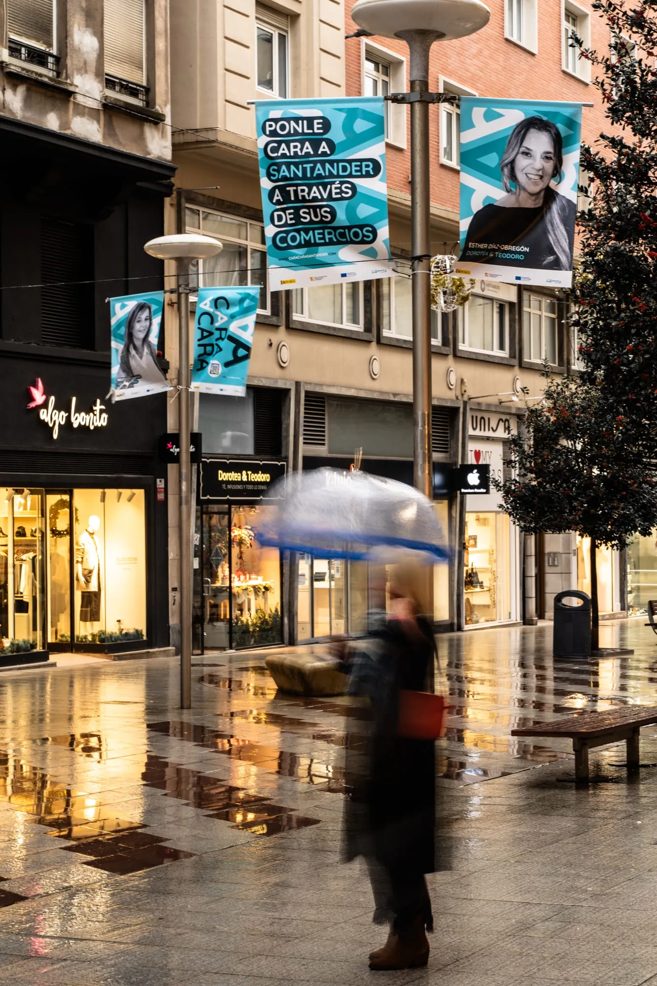 Banderolas azules de la campaña con el retrato de una comerciante en una calle comercial bajo la lluvia