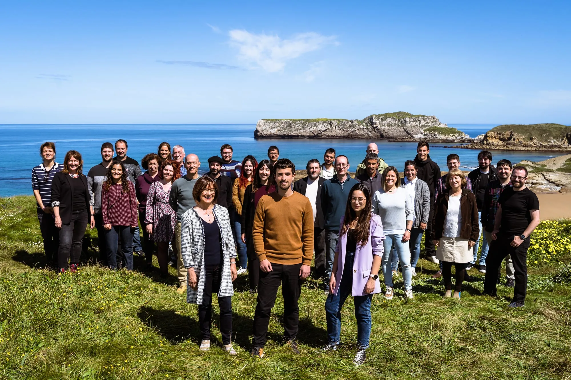 Toda la candidatura de Cantabristas en línea sobre la hierba, con el mar y los islotes de la costa al fondo