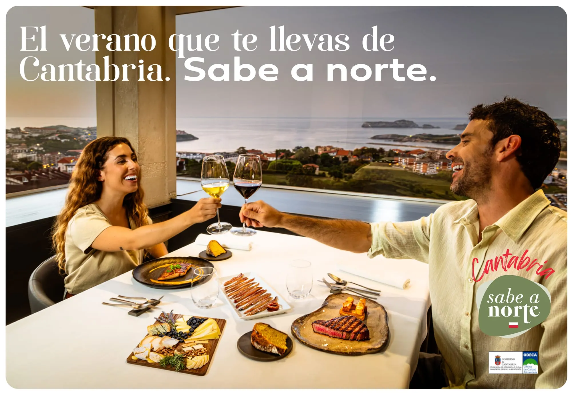 Cartel horizontal: la pareja brinda en el restaurante sobre la bahía bajo el claim El verano que te llevas de Cantabria. Sabe a norte