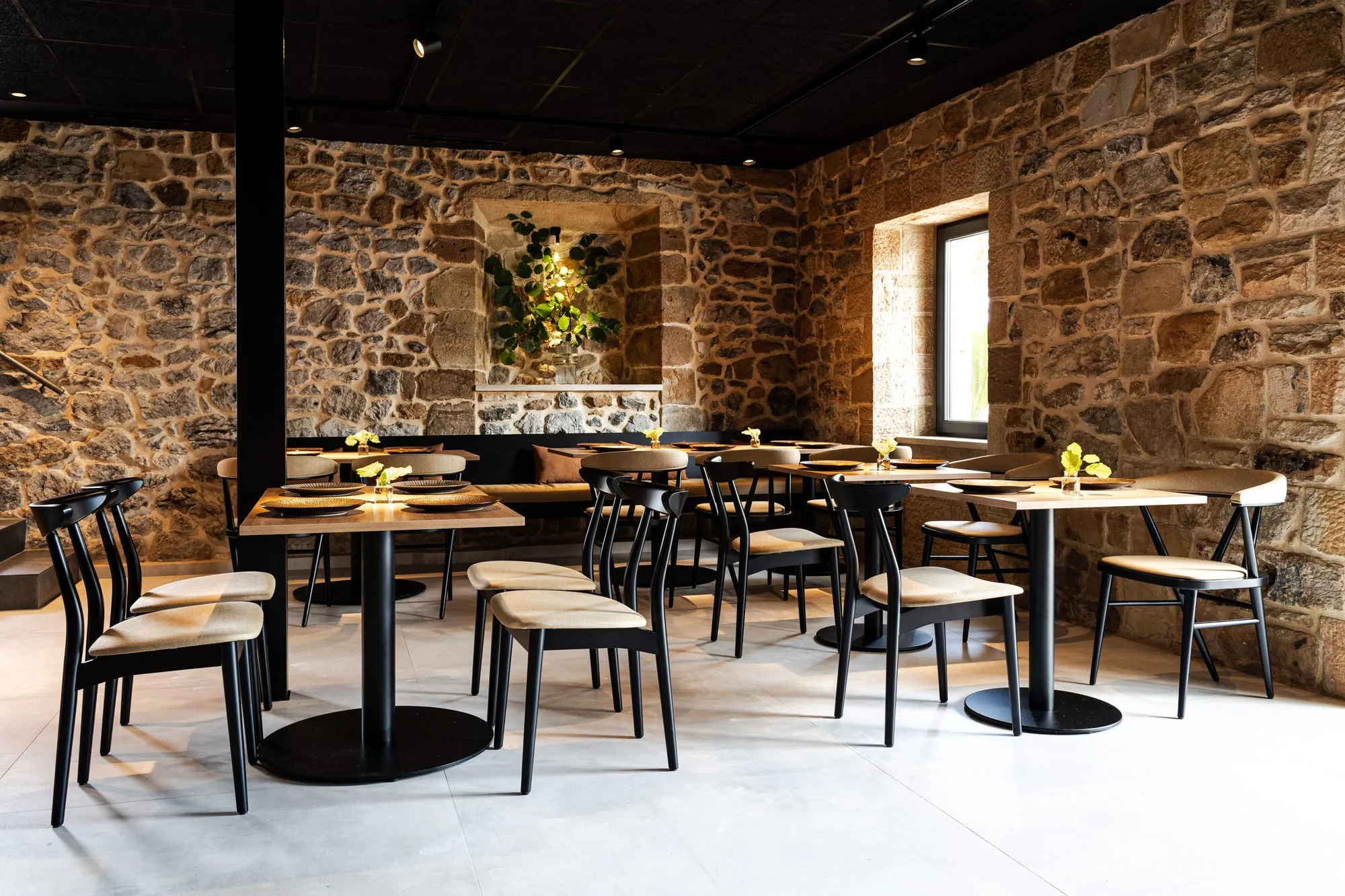 Comedor del restaurante Mitami con muros de piedra, mesas de madera y sillas negras