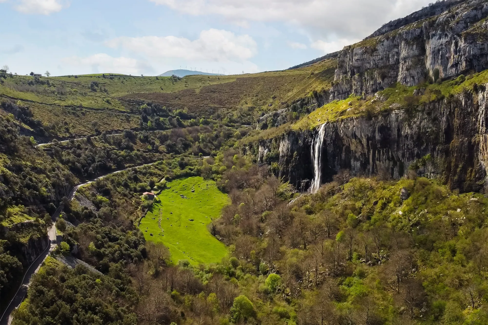 Cascada cayendo por una gran pared de roca sobre el valle verde de Soba, vista desde el aire