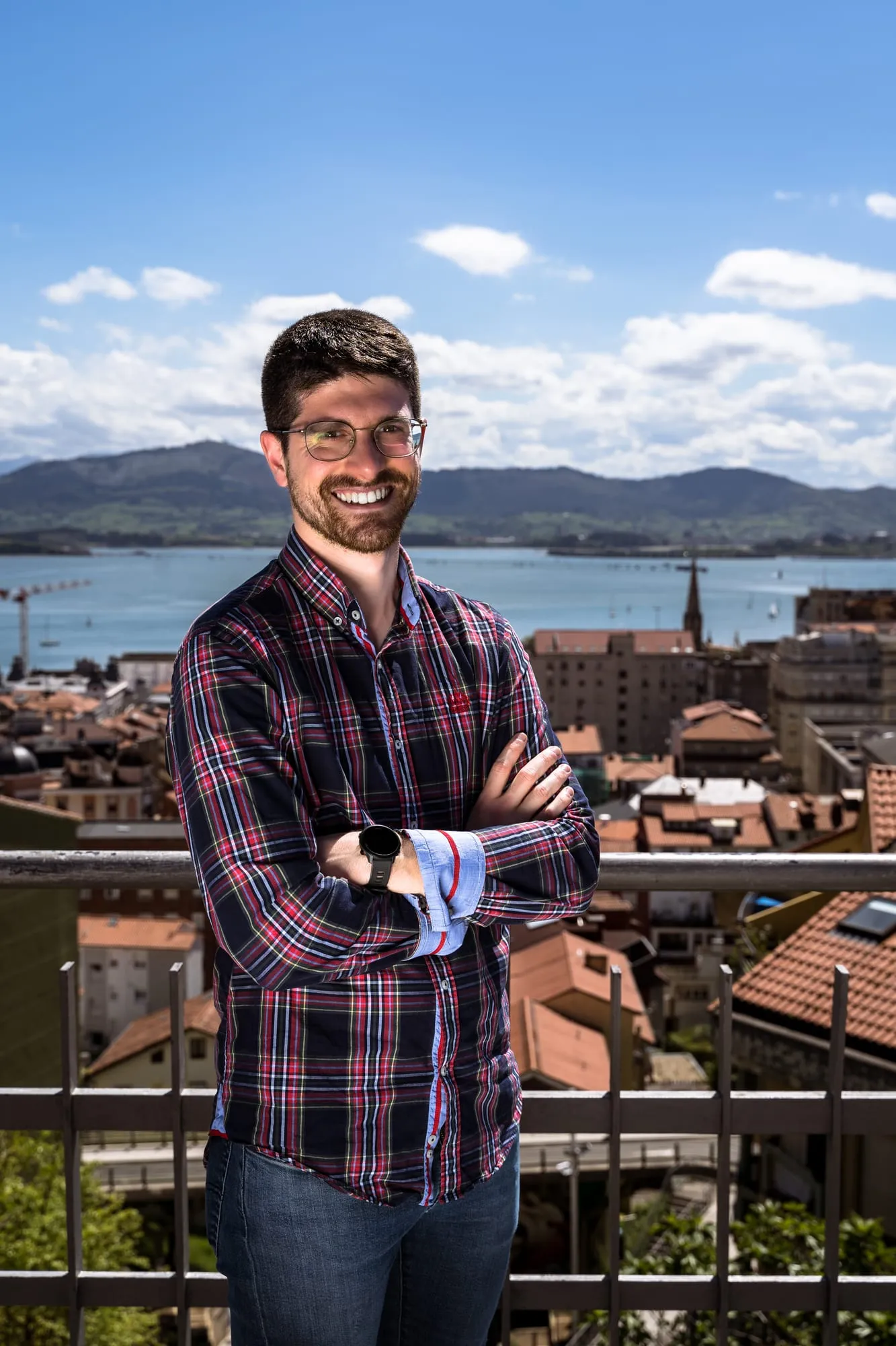 Candidato con camisa de cuadros sonríe en una terraza sobre los tejados y la bahía