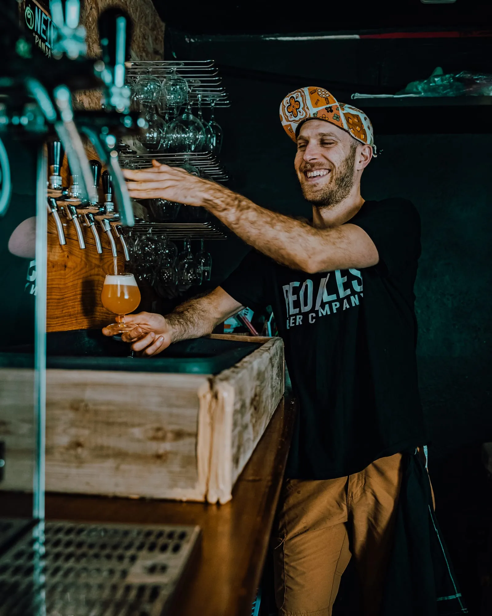 El cervecero sonríe mientras tira una cerveza turbia en copa desde los grifos