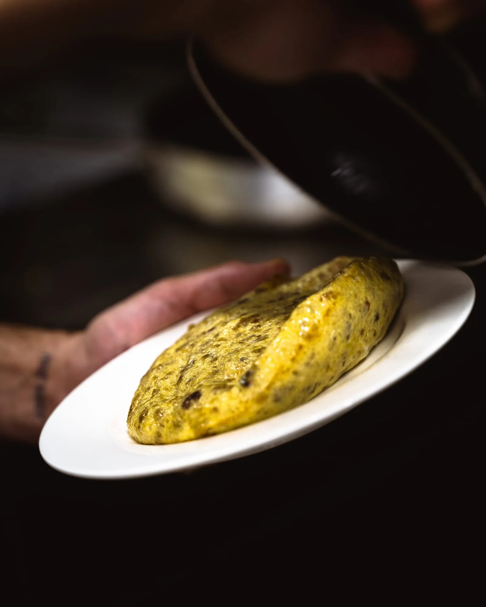 Persona con el bocadillo de tortilla en la mano, a punto de darle un bocado