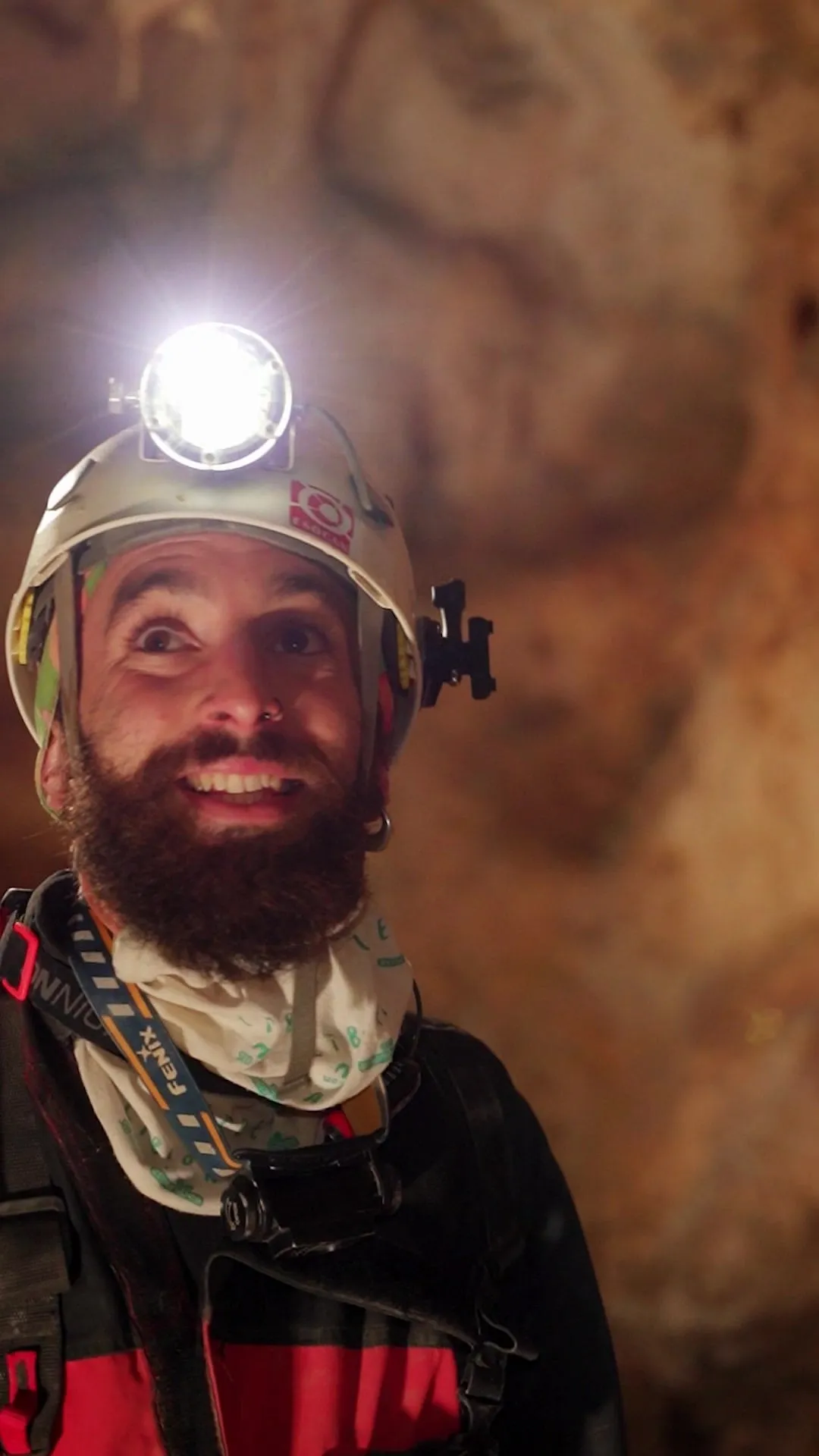 Espeleólogo sonriente con casco y frontal encendido dentro de una cueva de la comarca