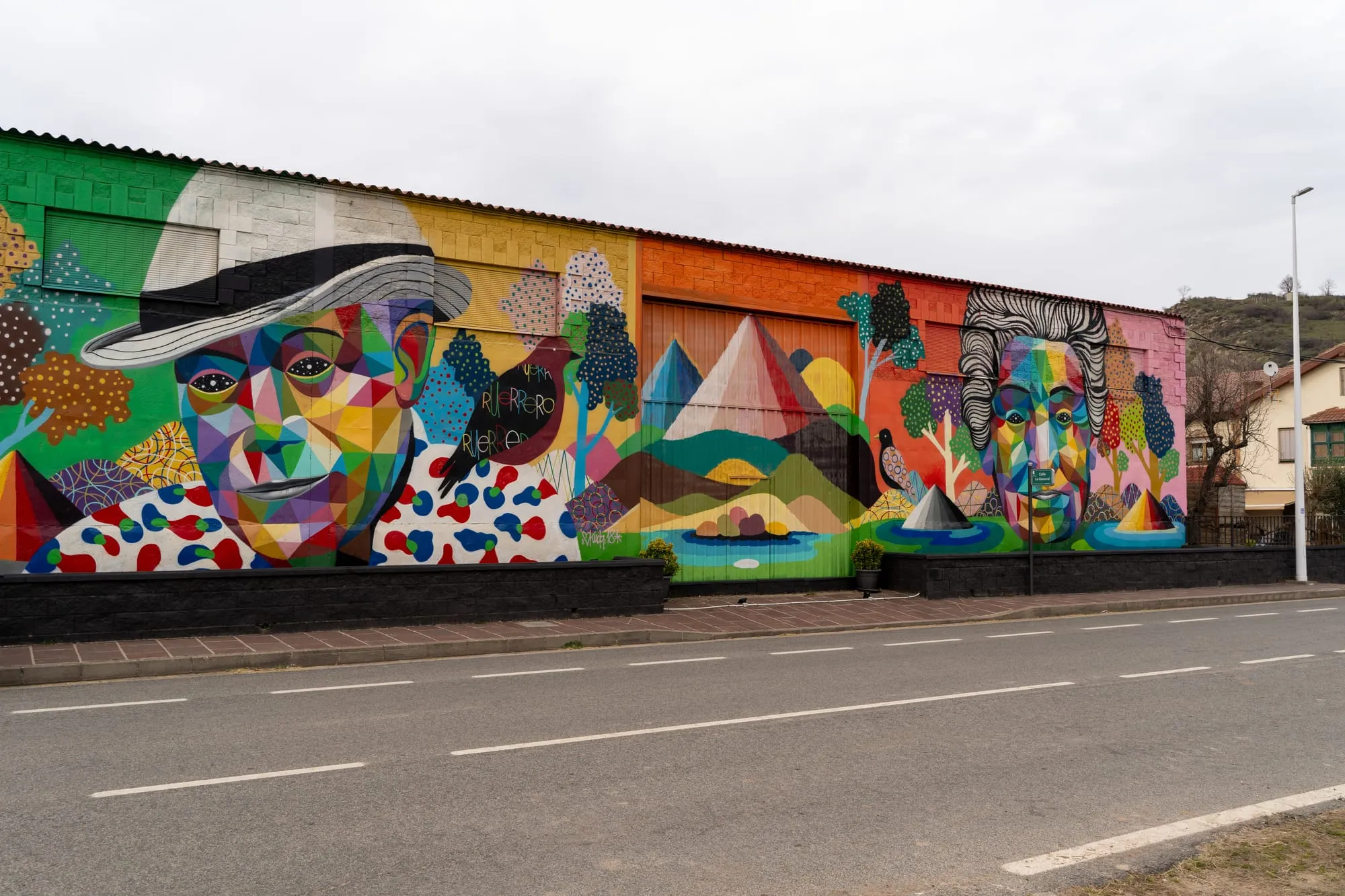 Mural de Okuda con dos rostros geométricos de colores sobre una nave en la carretera de Ruerrero