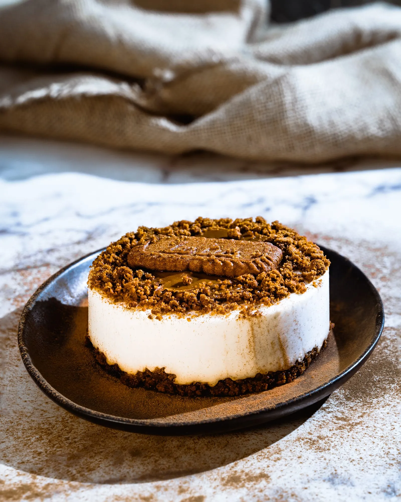 Tarta de queso con galleta caramelizada y base de galleta sobre plato de cerámica negra