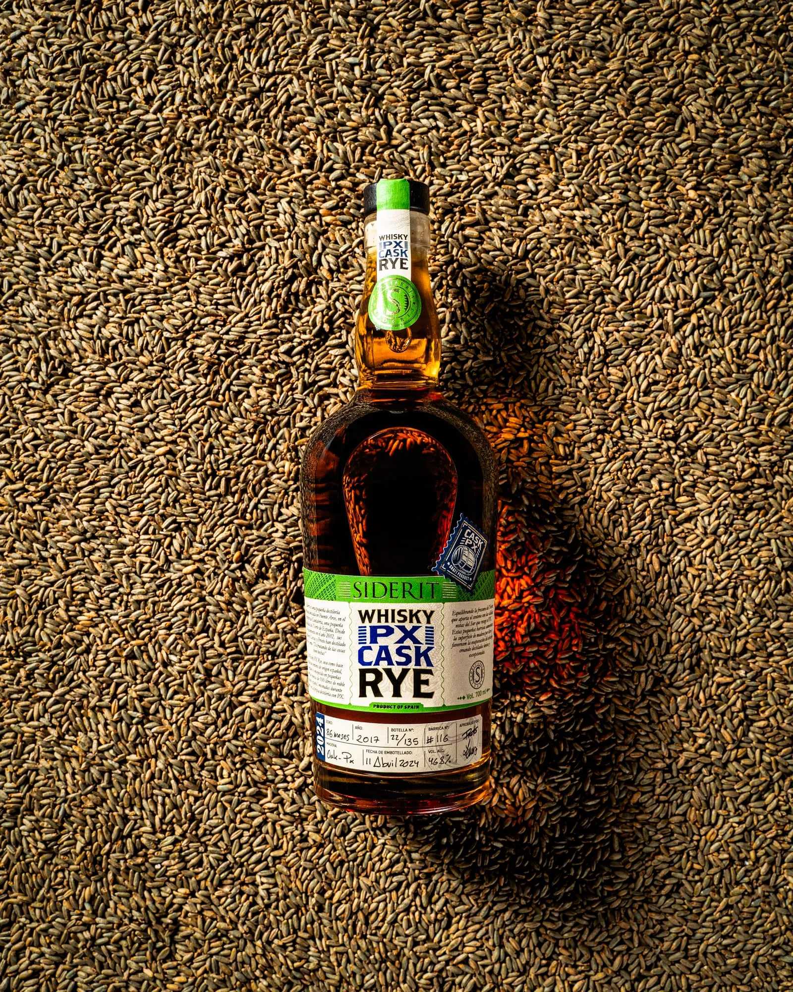 Whisky Siderit PX Cask Rye fotografiado cenital sobre granos de centeno
