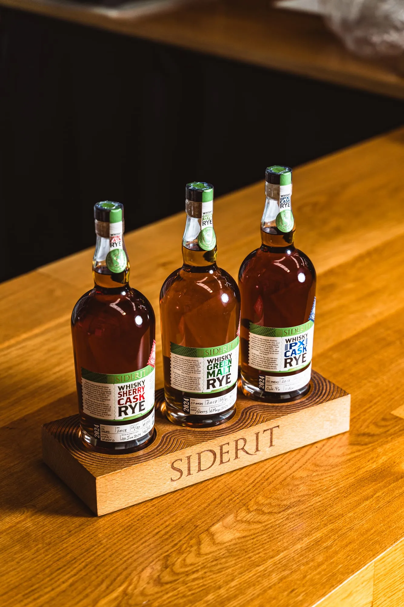 Tres whiskies Siderit, Sherry Cask, Green Malt y PX Cask, en un expositor de madera grabado