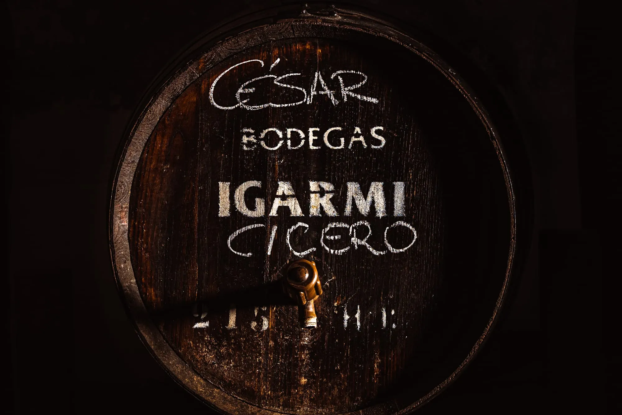 Barril de madera antiguo con César, Bodegas Igarmi y Cicero escritos a tiza en la bodega