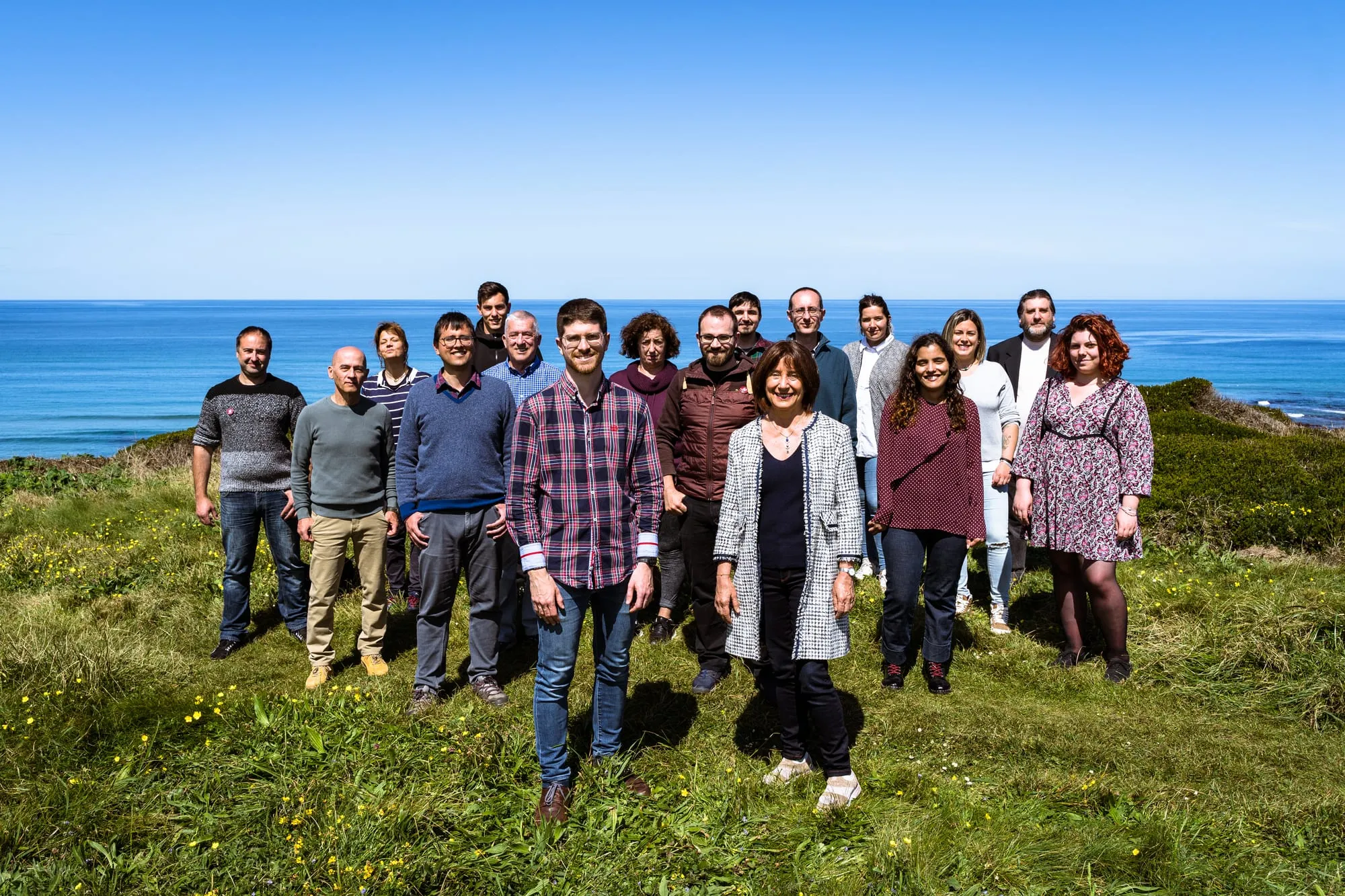 Grupo de la candidatura de pie en la hierba frente al mar, con una candidata al frente