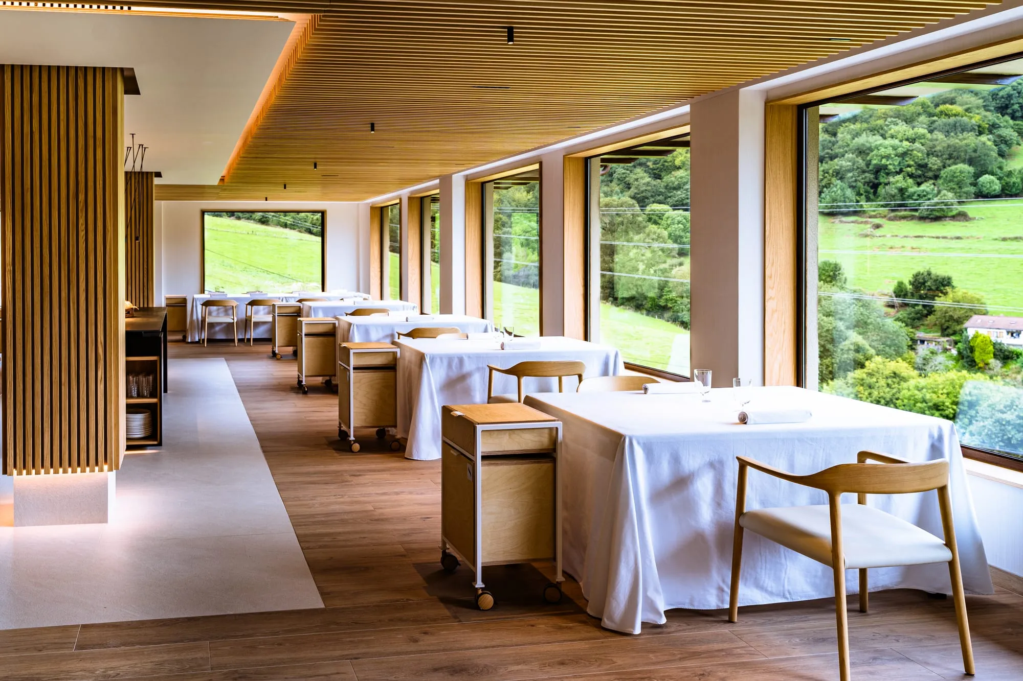 Comedor del Restaurante Solana con techo de madera y ventanales abiertos a los prados de Ampuero
