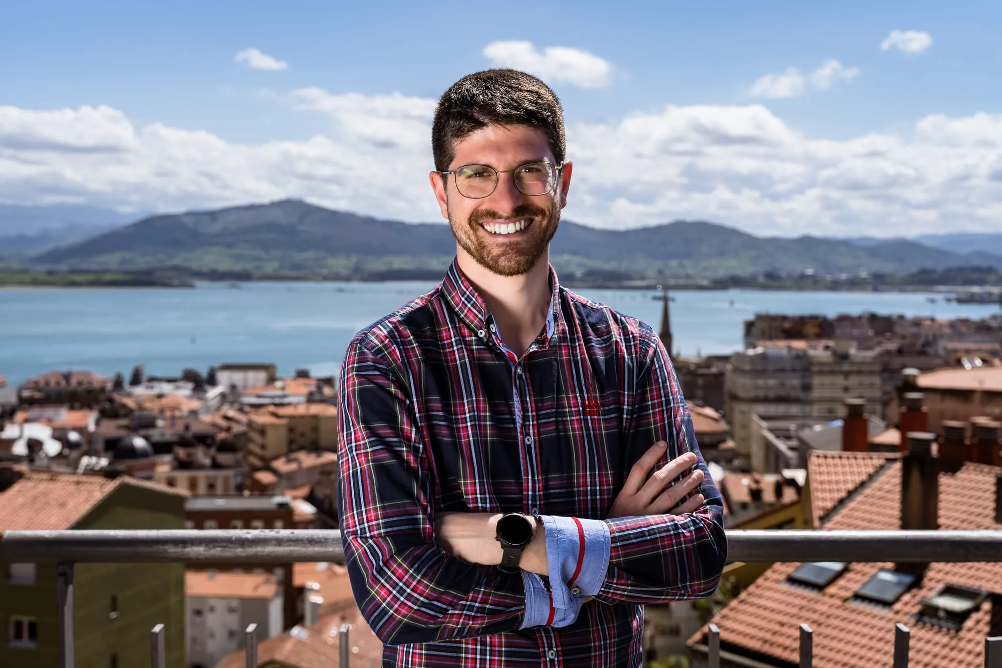 Candidato con los brazos cruzados en una terraza con vistas a los tejados y la bahía