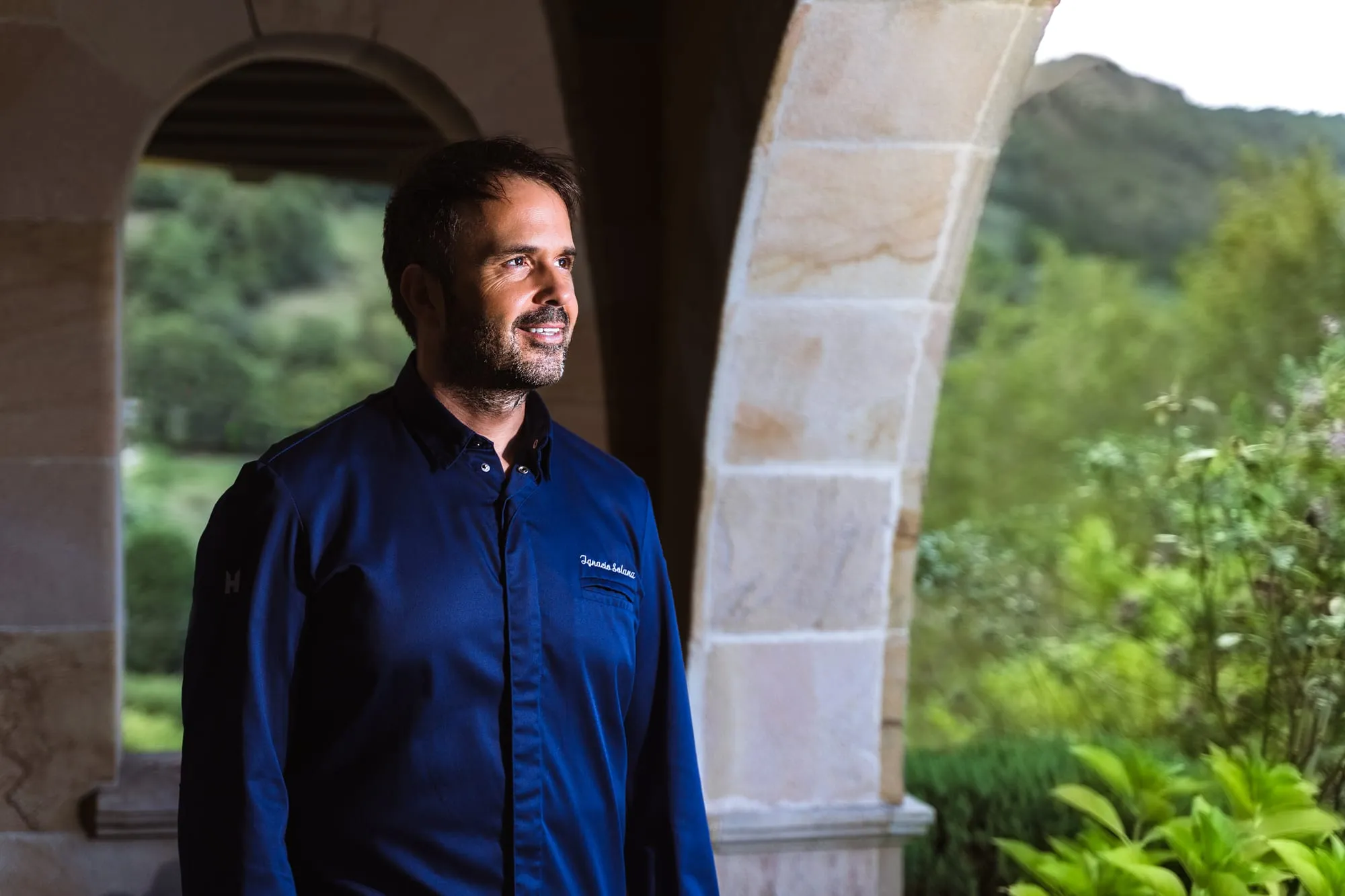 El chef Nacho Solana con chaquetilla azul bajo los arcos de piedra del restaurante