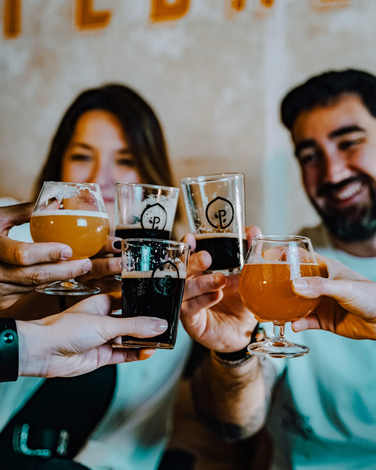 Brindis de cuatro amigos con copas de IPA turbia y vasos de cerveza negra
