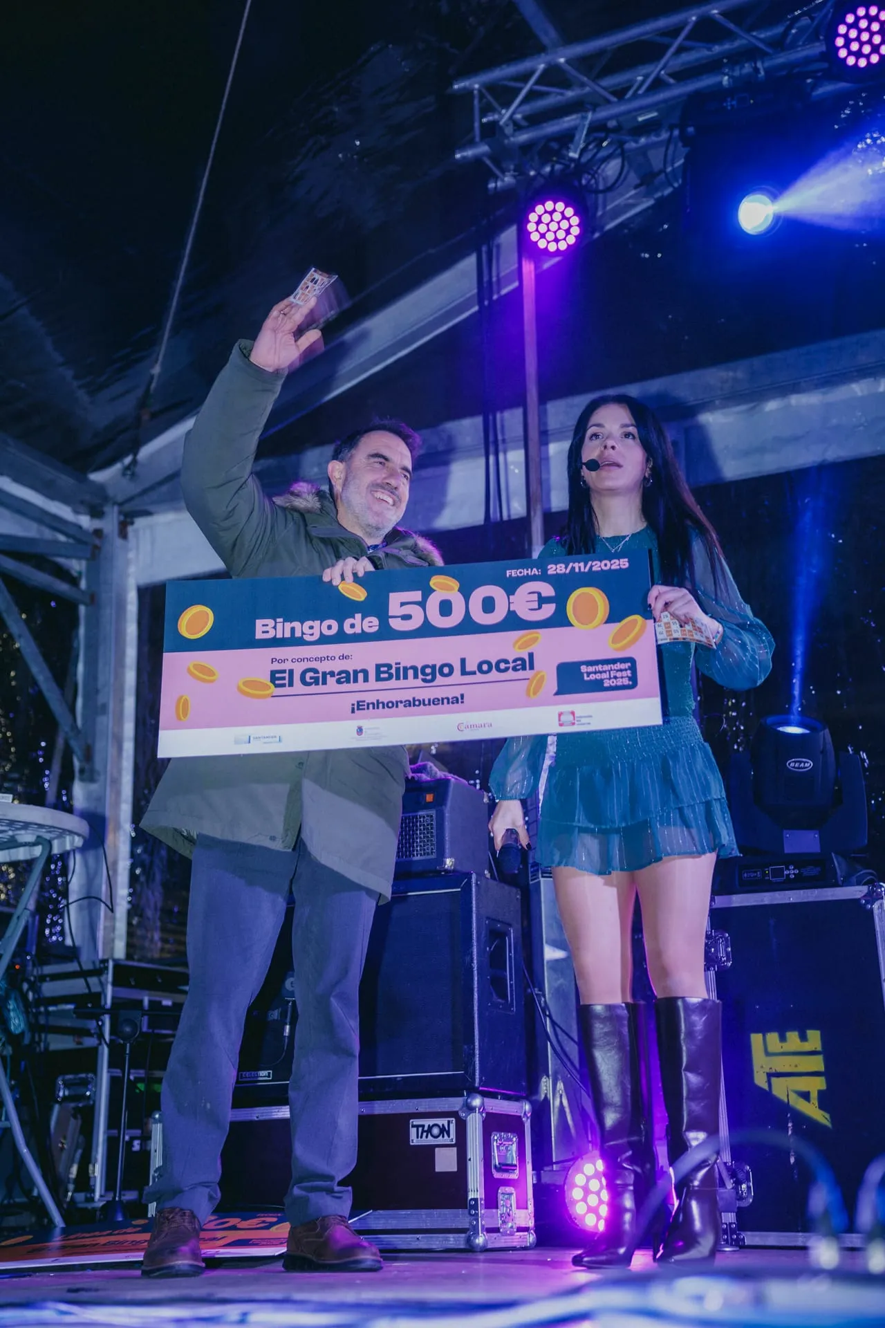 Ganador del bingo de 500 euros con el cheque gigante junto a la presentadora sobre el escenario