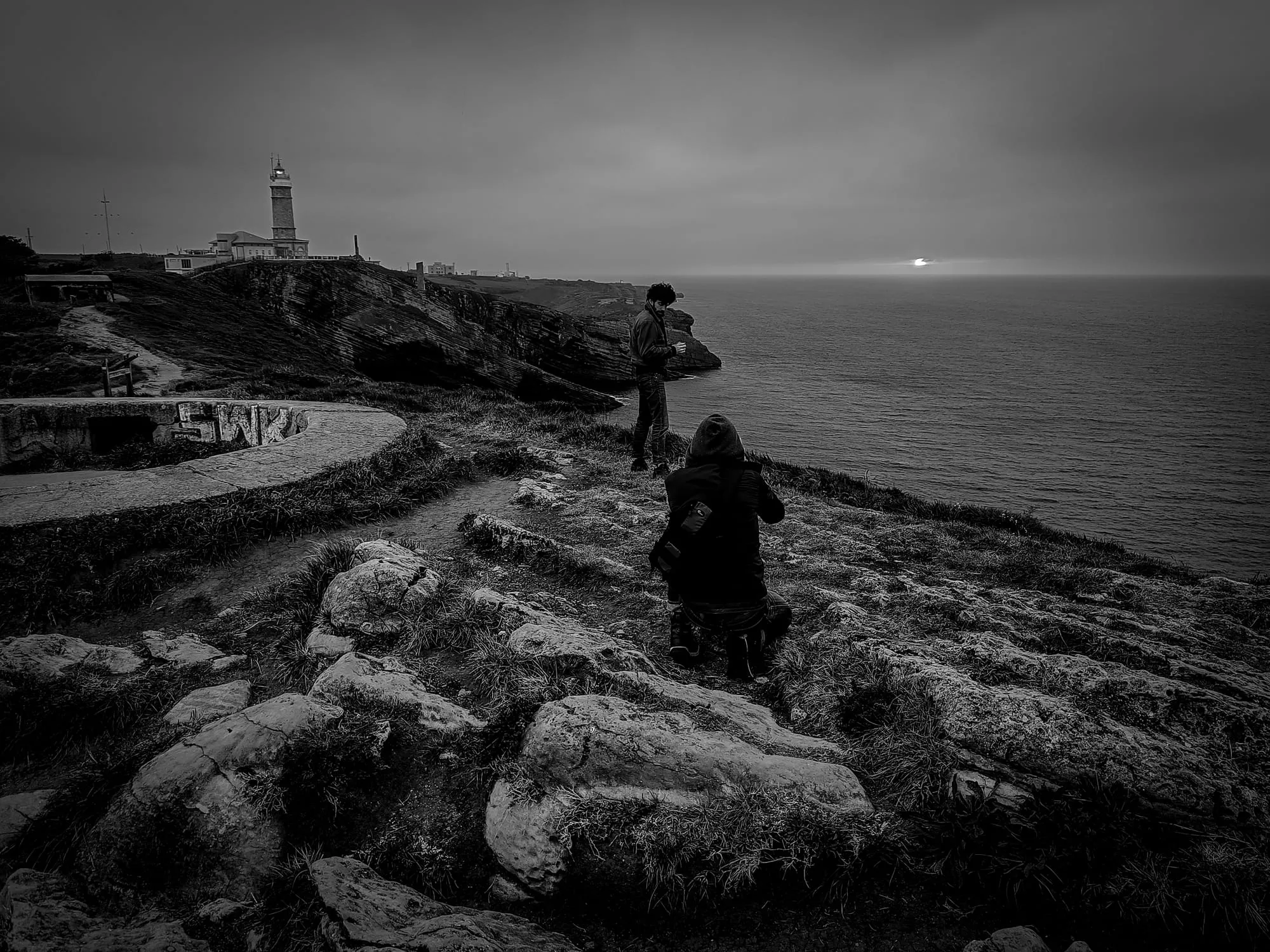 Fotógrafo del equipo retratando al protagonista al borde del acantilado de Cabo Mayor, con el sol bajo sobre el mar