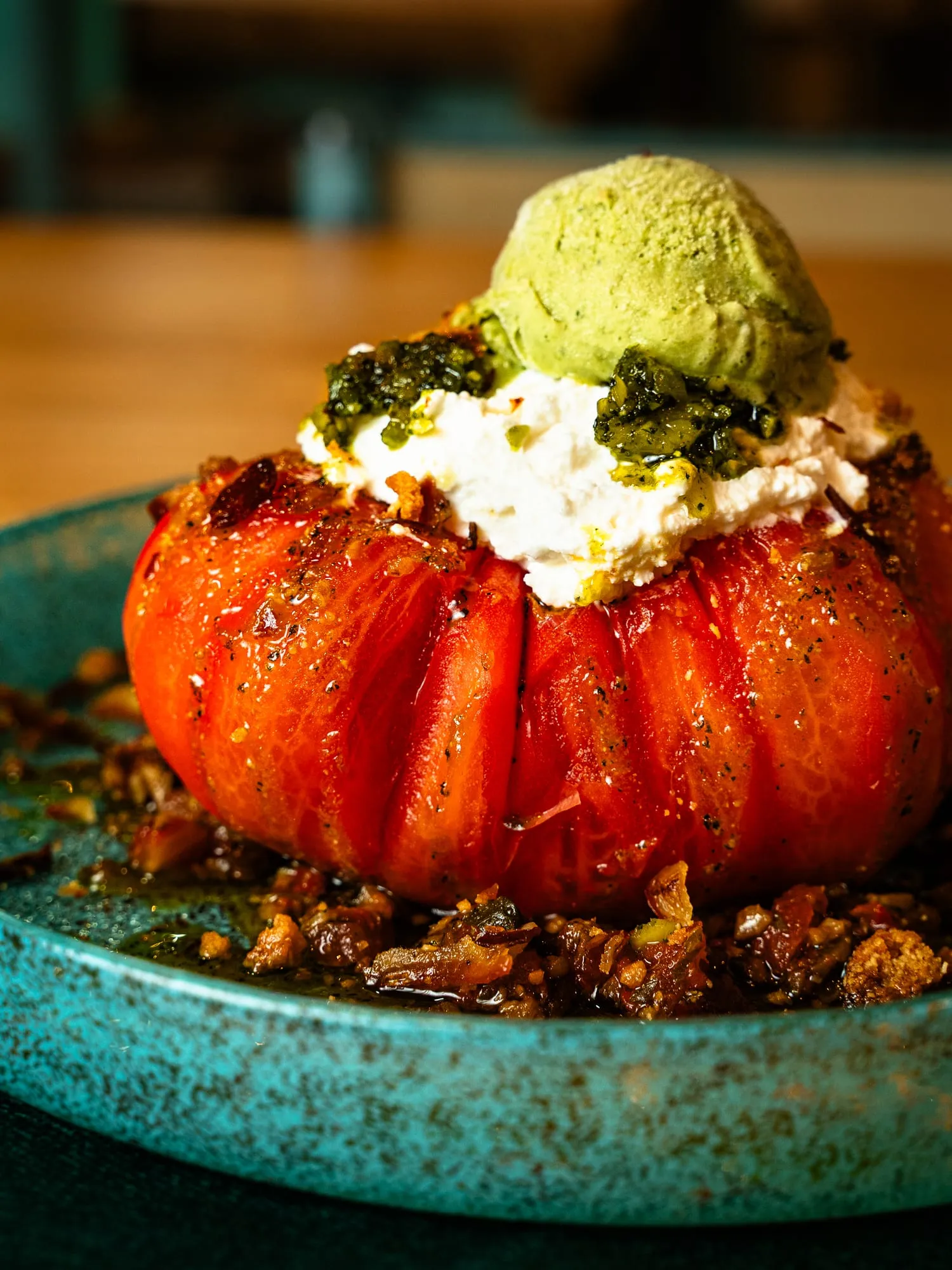 Tomate asado relleno de queso cremoso con pesto y helado verde sobre crumble