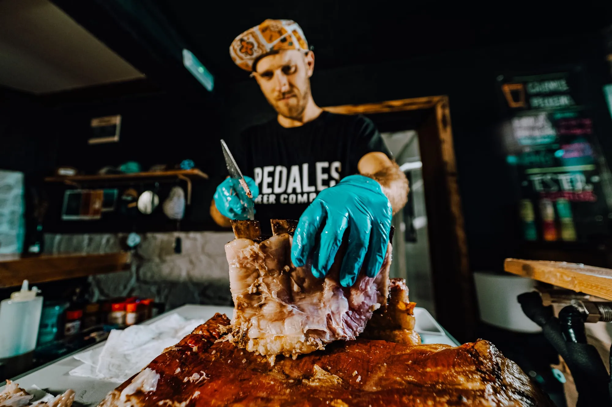 El cocinero corta un costillar asado con guantes azules en la cocina del local