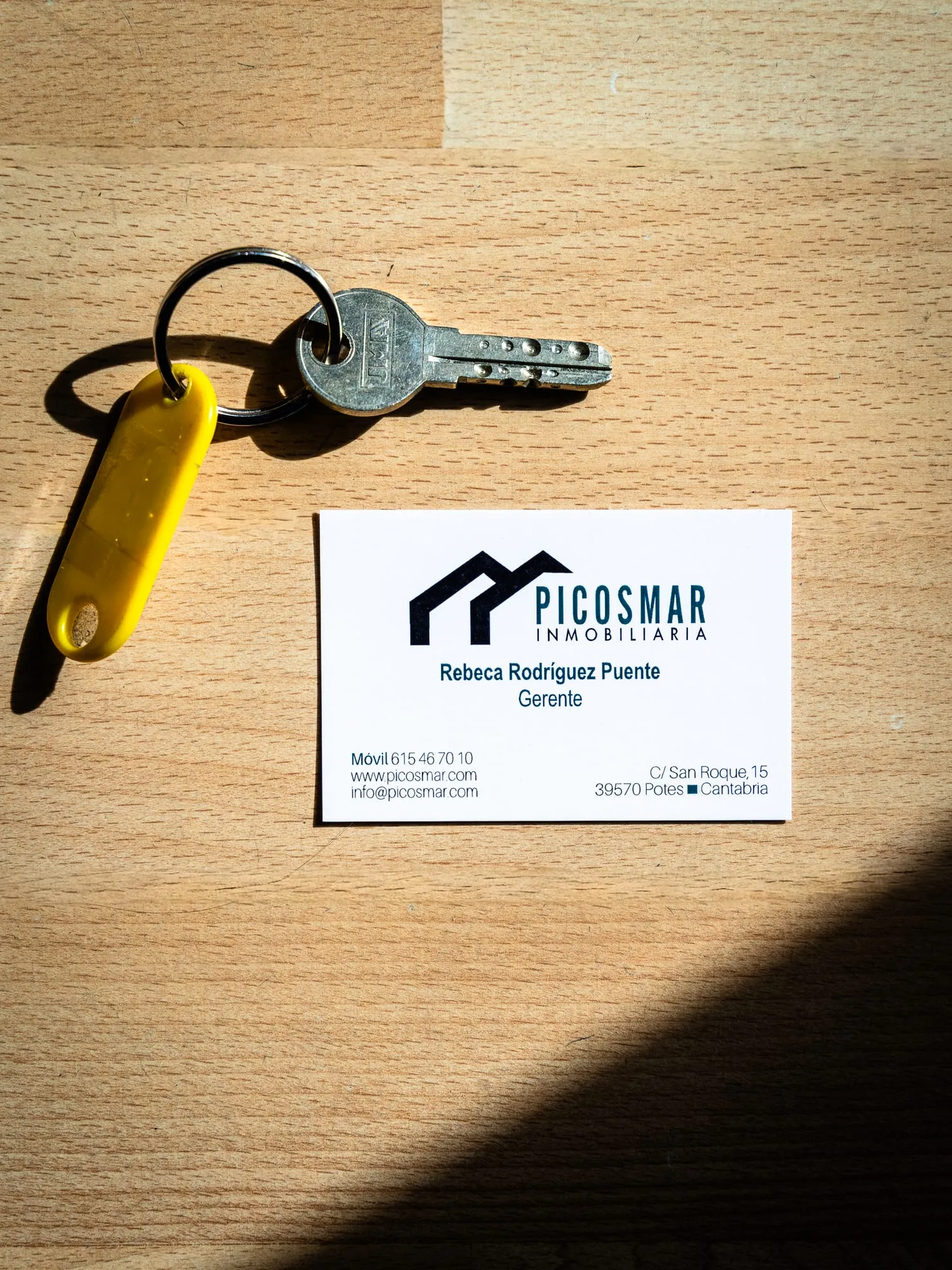 Llaves y tarjeta de Picos Mar Inmobiliaria sobre una mesa de madera