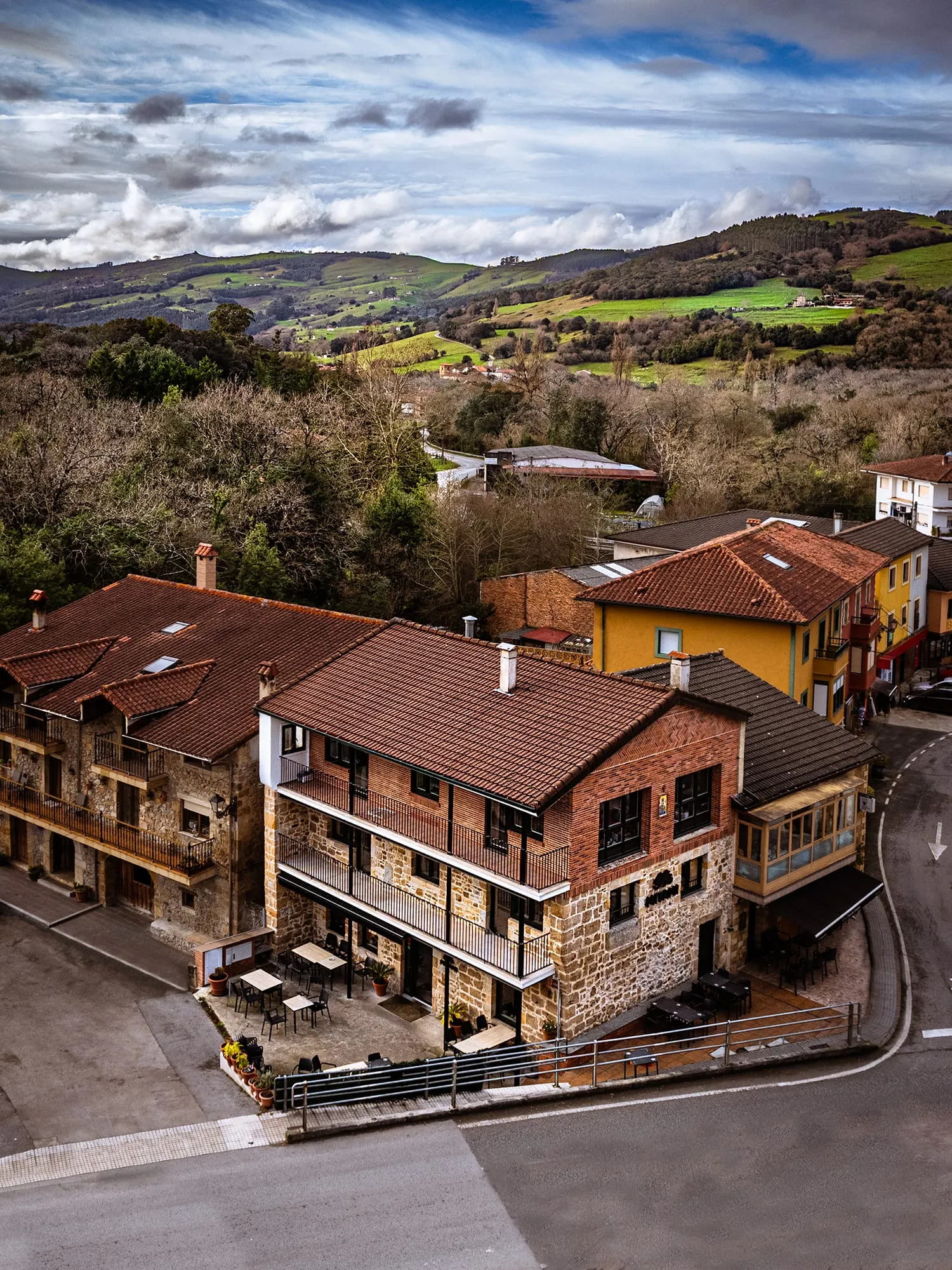 Vista aérea de la casona de piedra del restaurante en Bádames entre prados y colinas