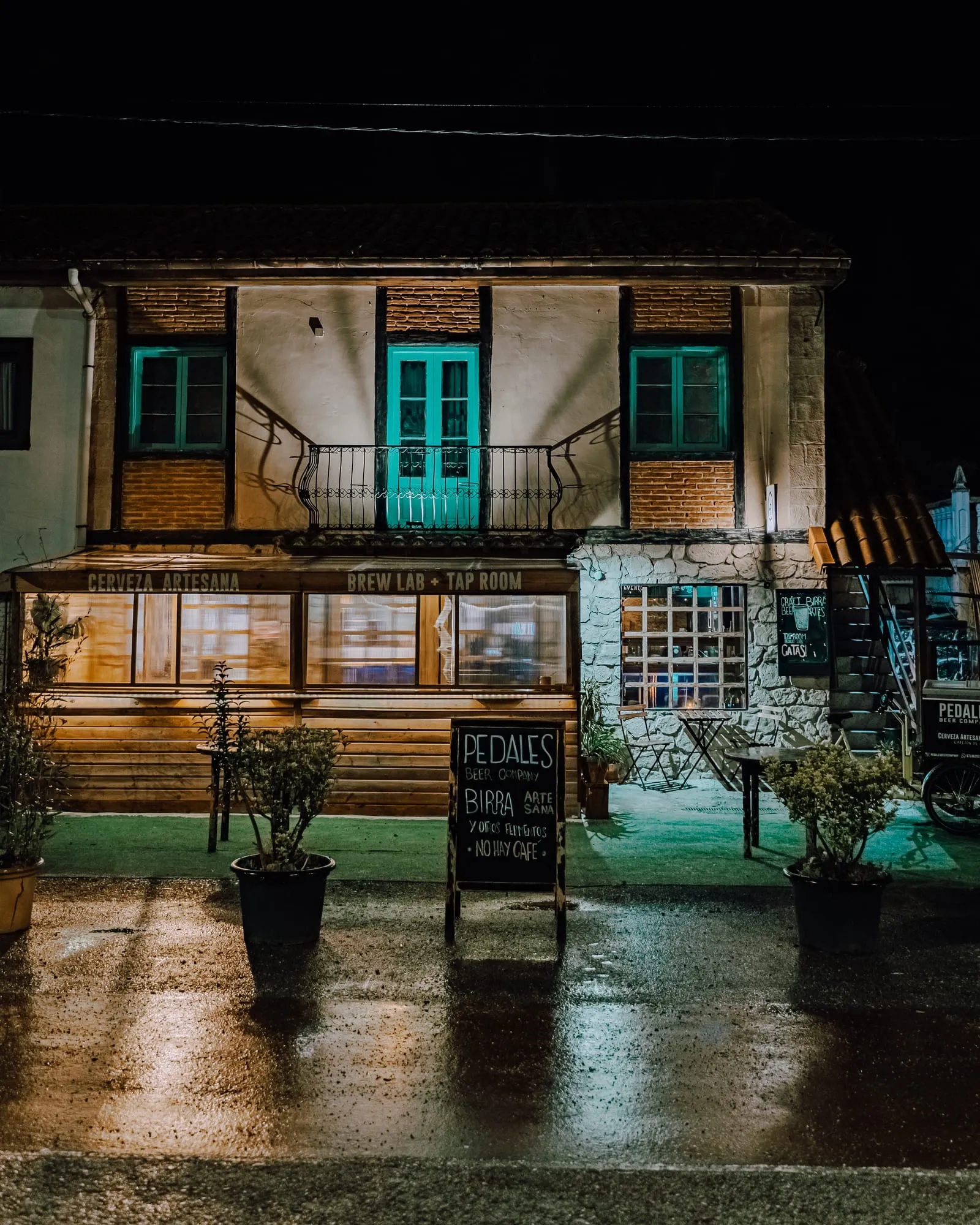 Fachada nocturna con los rótulos Cerveza artesana y Brew lab + Tap room y la pizarra de la entrada