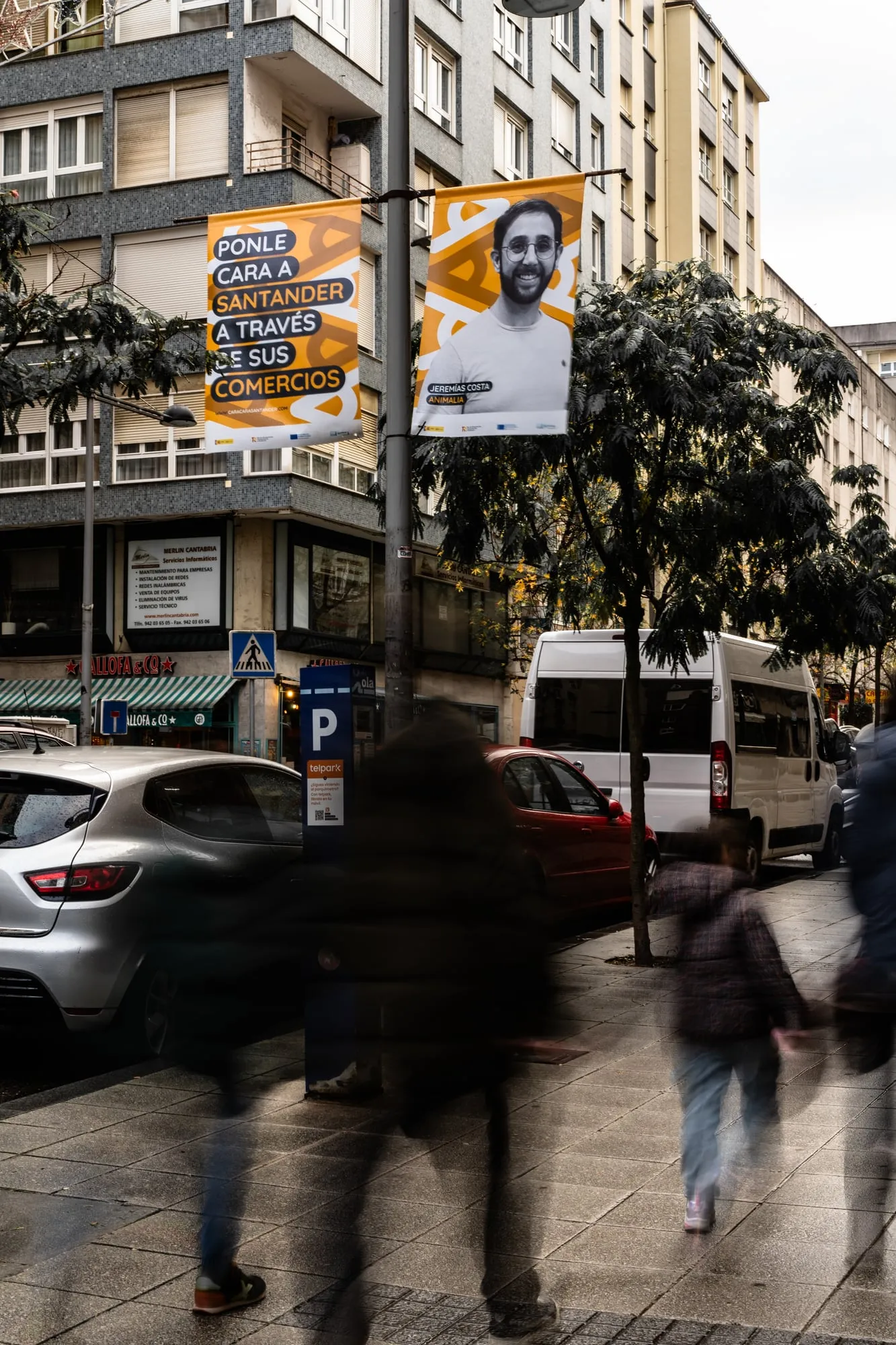 Banderolas de la campaña en una farola sobre una acera con peatones en movimiento