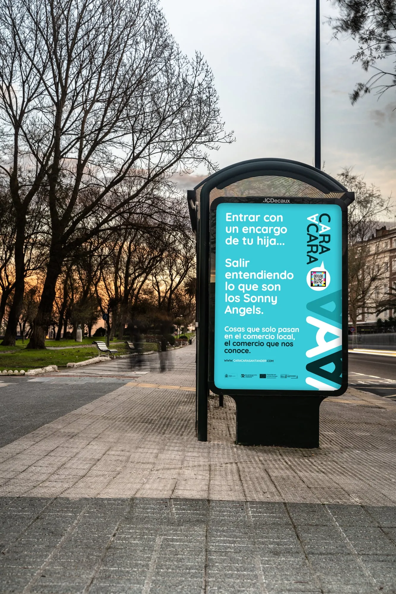 Mupi de la campaña en un paseo arbolado de Santander al anochecer