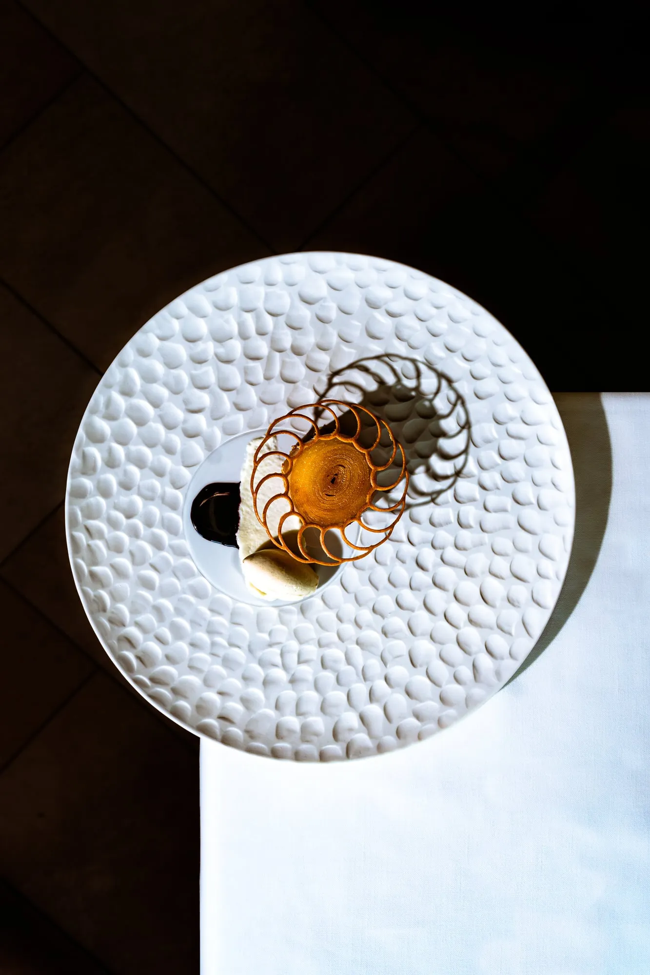 Bocado sobre un plato blanco de relieve, visto desde arriba sobre fondo oscuro