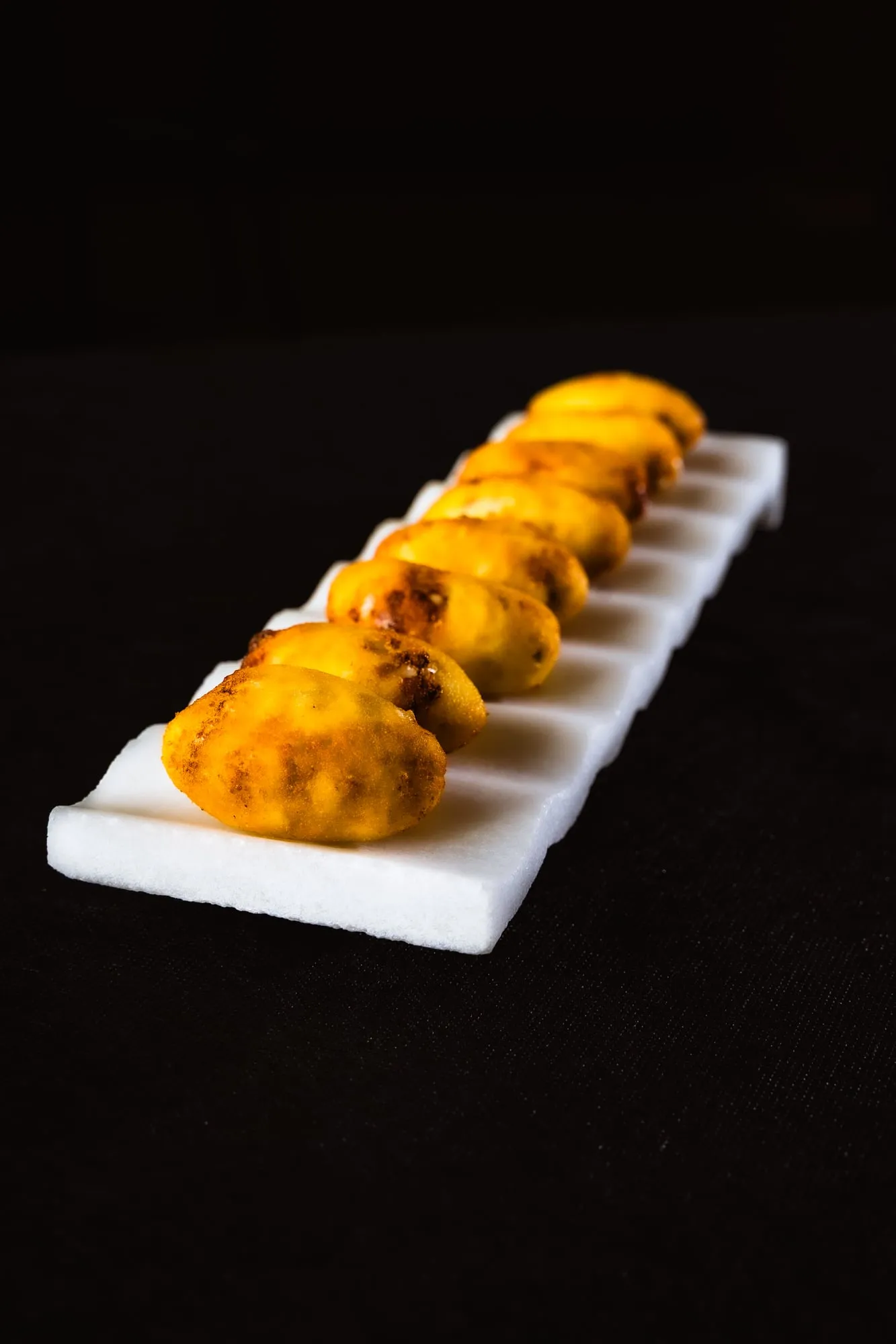 Fila de croquetas doradas sobre una bandeja blanca alargada